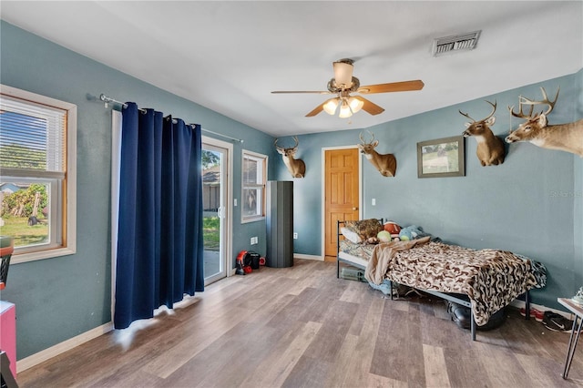 bedroom with visible vents, a ceiling fan, baseboards, and wood finished floors
