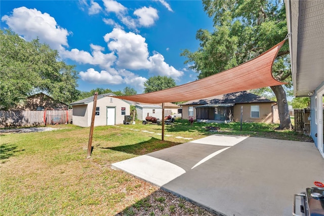exterior space with a front lawn, a patio area, fence, and an outbuilding