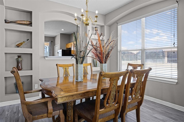 209 Rosso Dr, Davenport, FL 33837 - dining area with a chandelier, baseboards, wood finished floors, and arched walkways