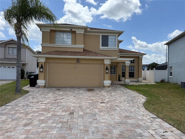 view of front of house with fence, an attached garage, a front lawn, stucco siding, and decorative driveway