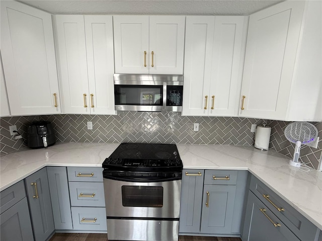 kitchen featuring stainless steel appliances, light stone counters, gray cabinets, and tasteful backsplash