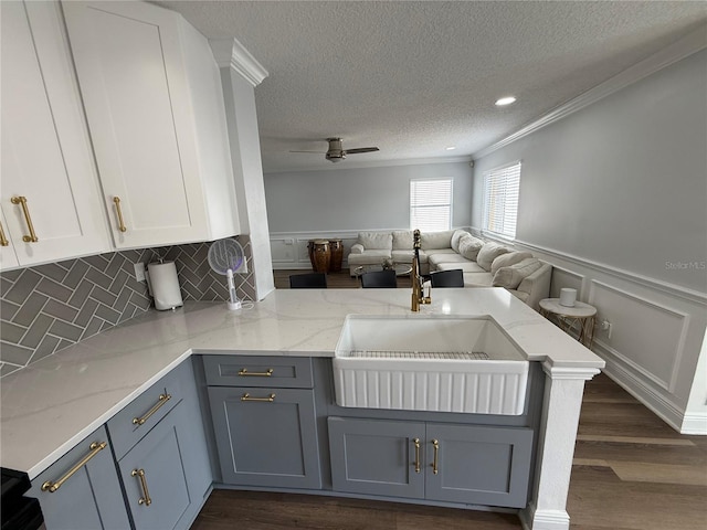 kitchen featuring a sink, a textured ceiling, a peninsula, and open floor plan