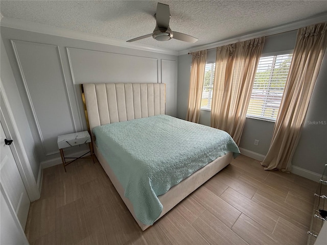 bedroom with a textured ceiling, baseboards, a ceiling fan, and a decorative wall