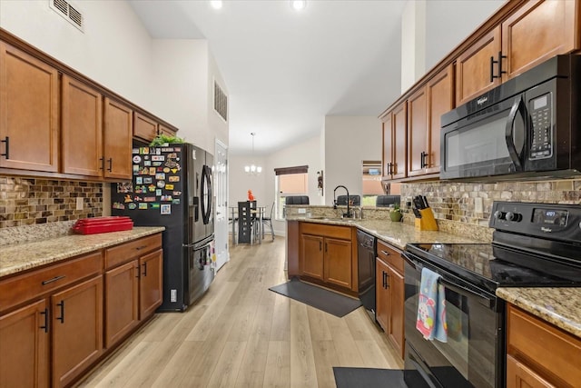 131 Highland Meadows Pl, Davenport, FL 33837 - kitchen with black appliances, brown cabinets, light wood finished floors, and backsplash