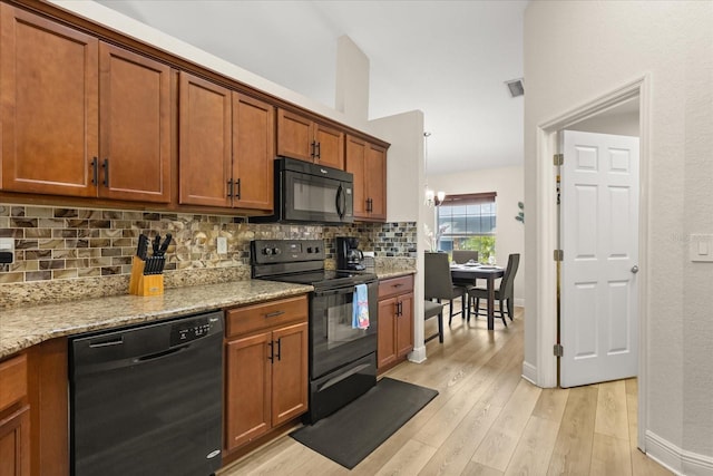 131 Highland Meadows Pl, Davenport, FL 33837 - kitchen with black appliances, decorative backsplash, brown cabinetry, light wood-style flooring, and lofted ceiling