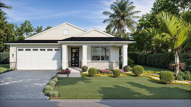 view of front of property with a garage, a front yard, decorative driveway, and stone siding