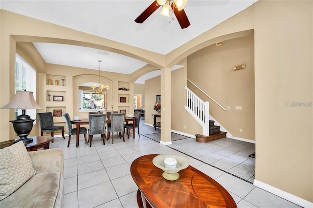 2632 Emerald Island Blvd, Kissimmee, FL 34747 - living area featuring arched walkways, ceiling fan with notable chandelier, stairs, baseboards, and light tile patterned floors