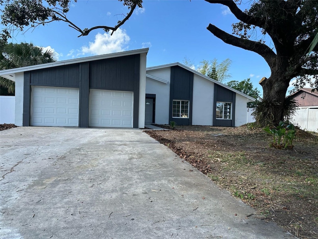 mid-century home with a garage, stucco siding, and driveway