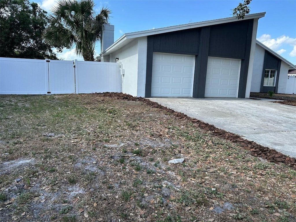 view of side of property featuring an attached garage, fence, and concrete driveway