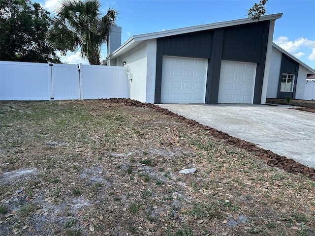 view of side of property featuring an attached garage, fence, and concrete driveway