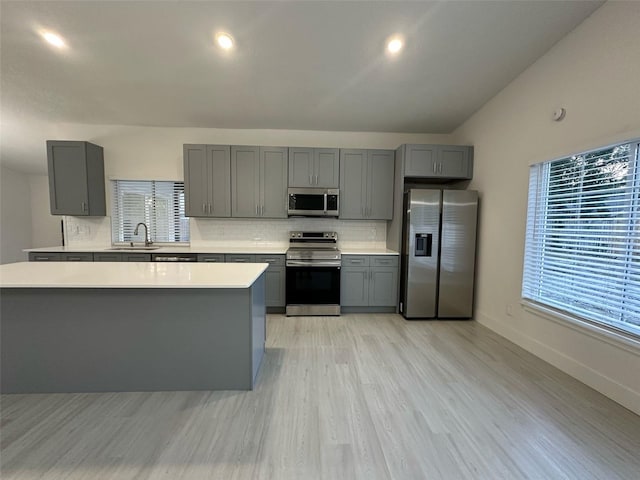 705 Wood Ln, Kissimmee, FL 34759 - kitchen featuring stainless steel appliances, gray cabinetry, decorative backsplash, light countertops, and light wood-type flooring
