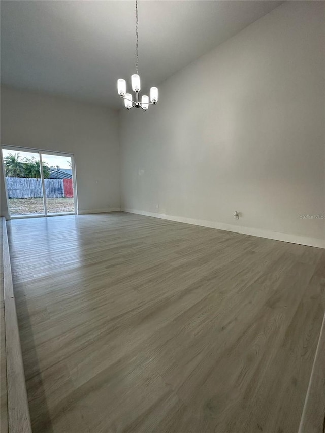 705 Wood Ln, Kissimmee, FL 34759 - empty room featuring wood finished floors, baseboards, and a notable chandelier