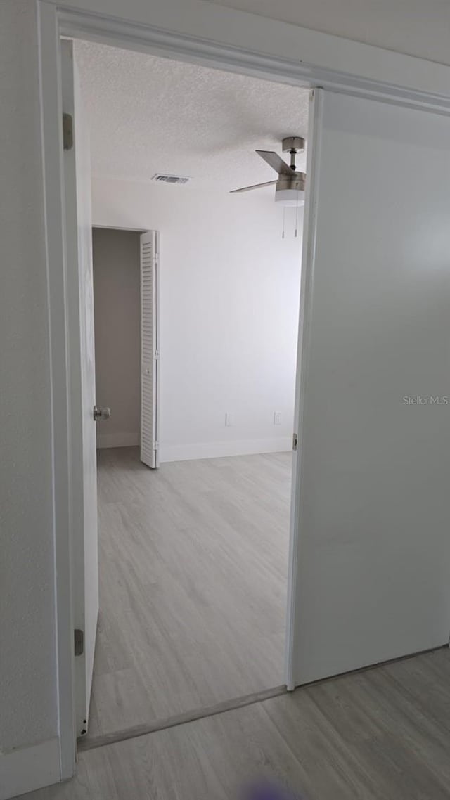 705 Wood Ln, Kissimmee, FL 34759 - hallway featuring baseboards, visible vents, a textured ceiling, and wood finished floors
