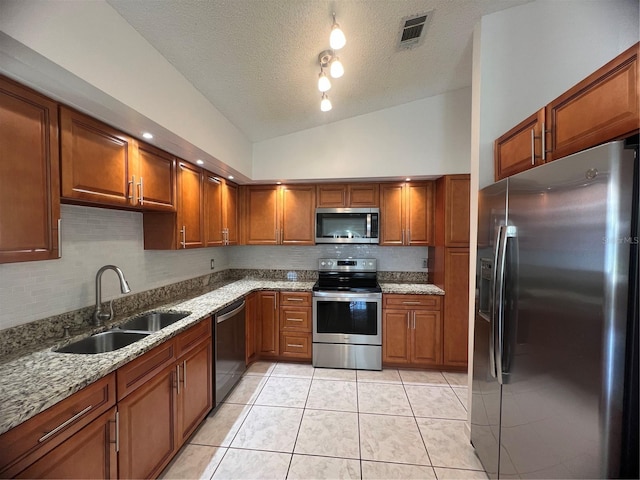 849 Long Bay Ct, Kissimmee, FL 34741 - kitchen with stainless steel appliances, a sink, vaulted ceiling, backsplash, and brown cabinets