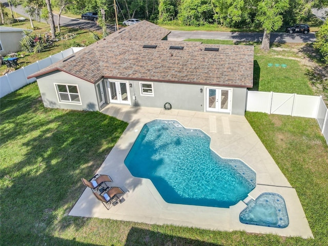view of swimming pool with a fenced backyard, a yard, and french doors