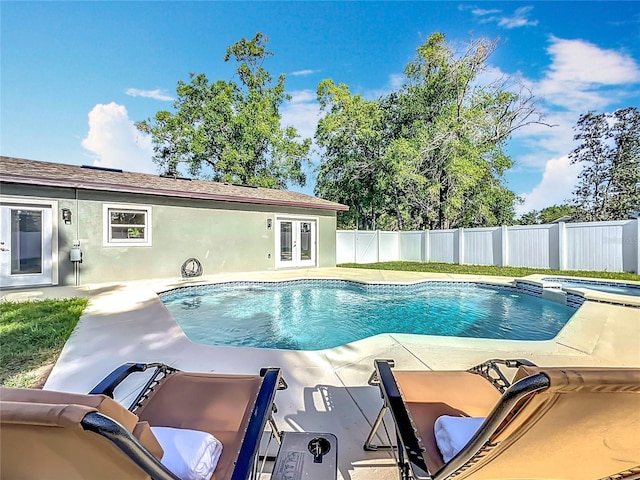 view of swimming pool featuring a patio area, fence, french doors, and a pool with connected hot tub
