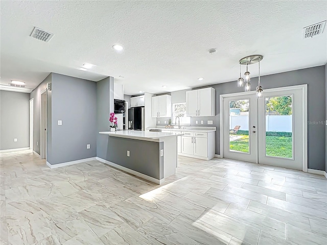 kitchen featuring light countertops, a peninsula, black refrigerator with ice dispenser, and visible vents