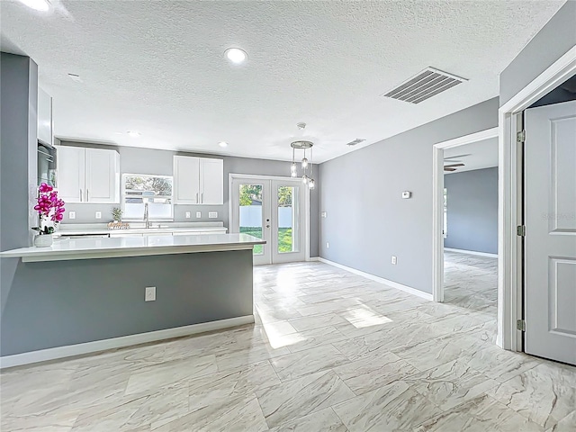 kitchen featuring visible vents, light countertops, white cabinets, a peninsula, and marble finish floor