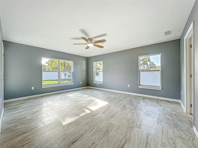 spare room featuring ceiling fan, visible vents, and baseboards
