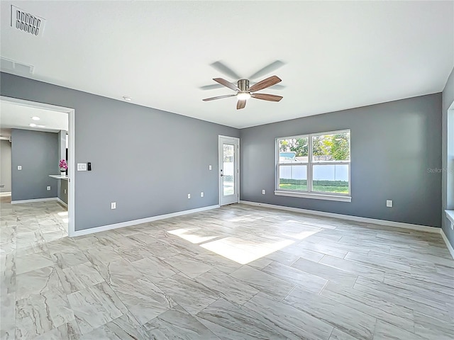 spare room with ceiling fan, visible vents, baseboards, and marble finish floor