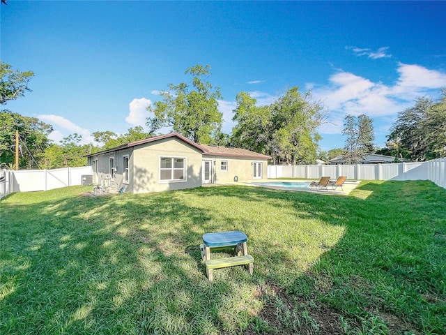 rear view of property featuring a lawn, a fenced backyard, stucco siding, and a fenced in pool