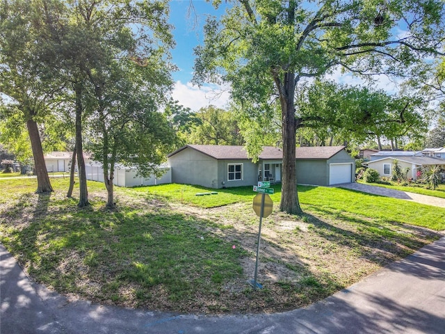 single story home featuring aphalt driveway, fence, a front yard, stucco siding, and an attached garage