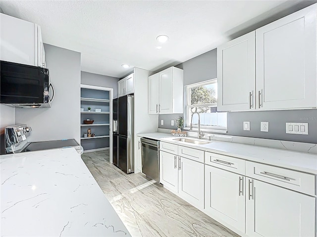 kitchen featuring white cabinets, light stone counters, a sink, marble finish floor, and stainless steel appliances