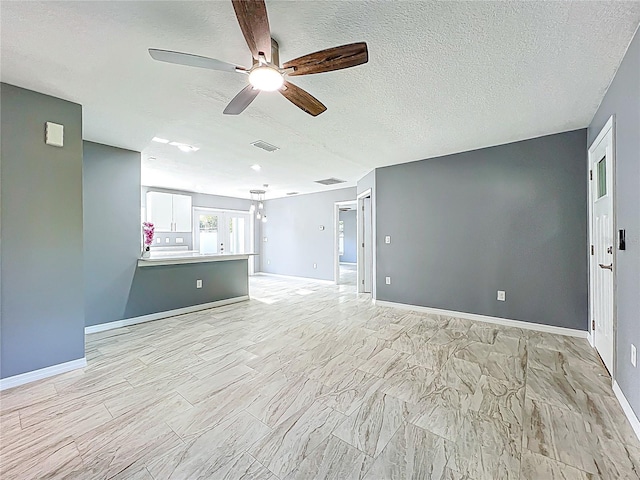 unfurnished living room with visible vents, a textured ceiling, baseboards, and ceiling fan