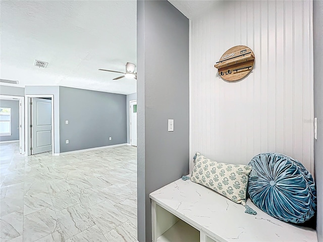 mudroom featuring a ceiling fan, wood walls, visible vents, and marble finish floor