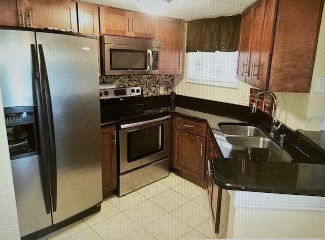 kitchen featuring a sink, appliances with stainless steel finishes, light tile patterned floors, and backsplash