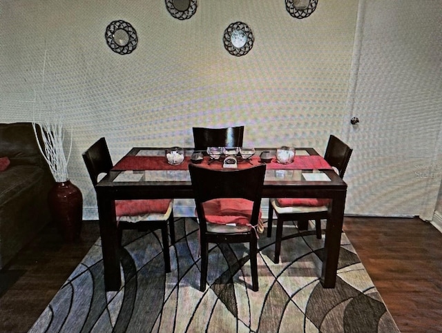 dining space featuring baseboards, wallpapered walls, and wood finished floors