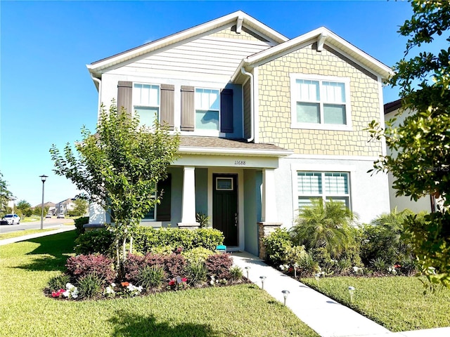 view of front facade featuring a front lawn, stucco siding, and covered porch