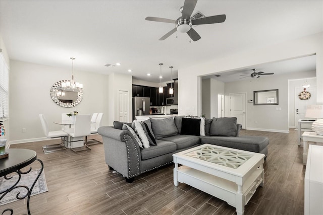 living room with baseboards, ceiling fan with notable chandelier, and dark wood-style flooring
