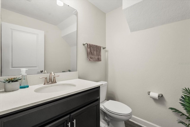 half bathroom with toilet, baseboards, wood finished floors, and vanity