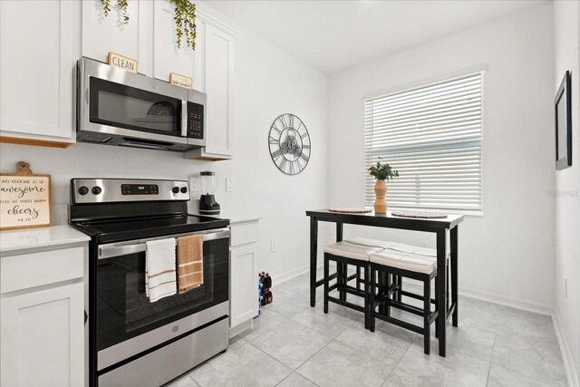 2156 Merrybells Dr, Kissimmee, FL 34746 - kitchen featuring appliances with stainless steel finishes, light countertops, white cabinetry, and baseboards