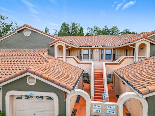 mediterranean / spanish house featuring stairs, stucco siding, and a tile roof