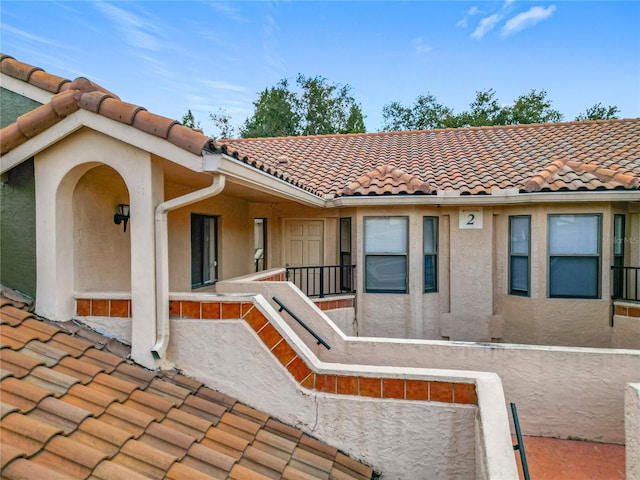exterior space with a tile roof and stucco siding