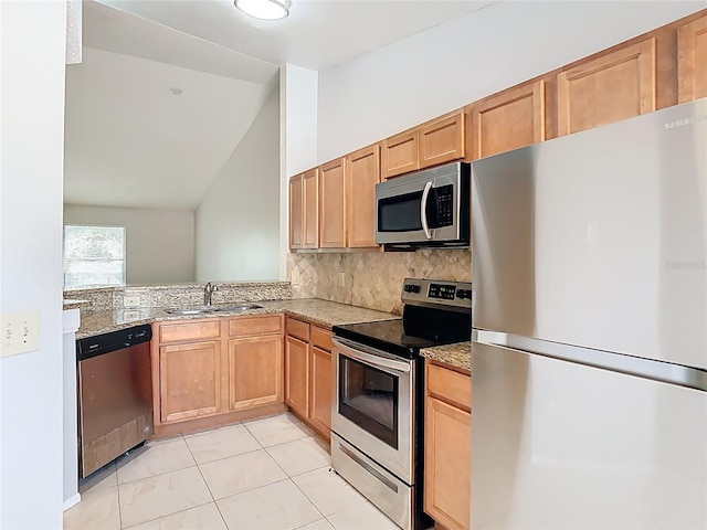kitchen with decorative backsplash, a sink, light tile patterned floors, vaulted ceiling, and stainless steel appliances