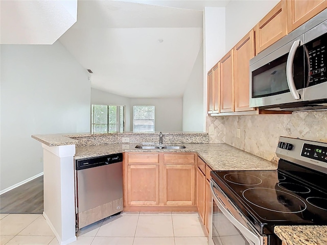kitchen with a sink, decorative backsplash, appliances with stainless steel finishes, and lofted ceiling