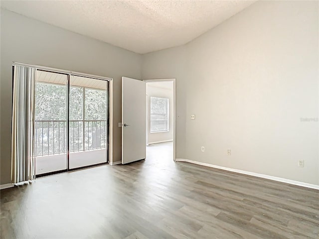 unfurnished room with baseboards, a textured ceiling, and wood finished floors