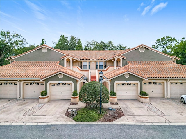 view of front of house with stucco siding, concrete driveway, and a tile roof