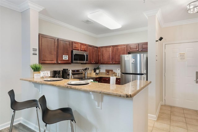 kitchen featuring ornamental molding, a peninsula, light stone countertops, a kitchen bar, and stainless steel appliances