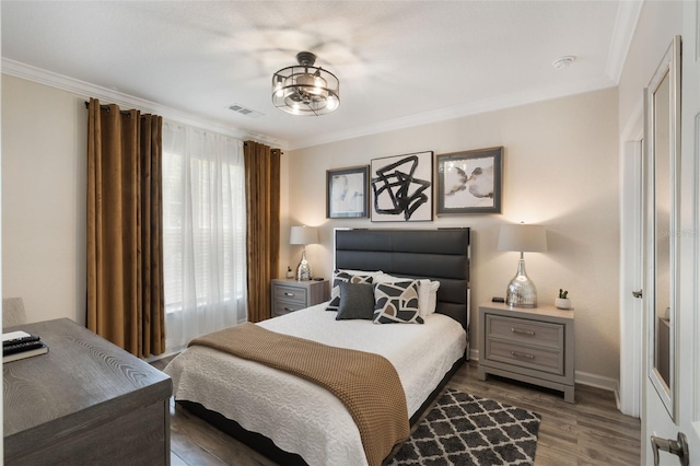 bedroom featuring crown molding, baseboards, visible vents, and wood finished floors