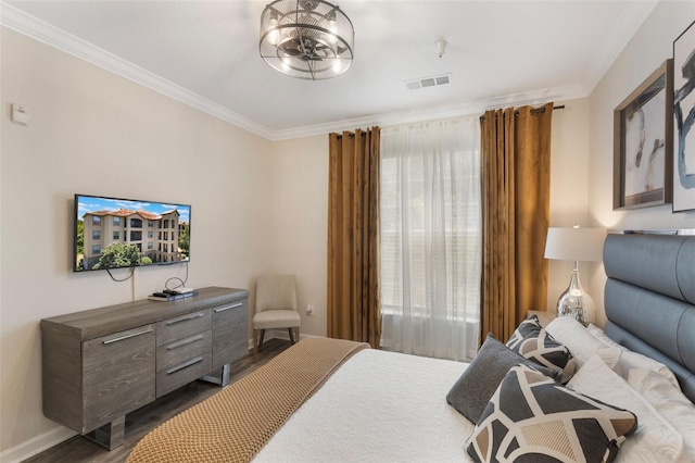 bedroom featuring visible vents, ornamental molding, baseboards, and wood finished floors