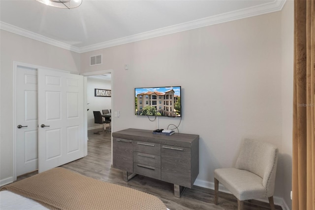 bedroom with crown molding, baseboards, wood finished floors, and visible vents