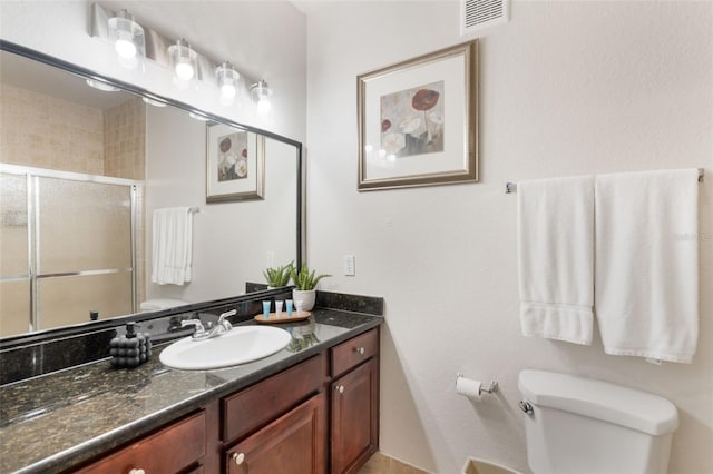 full bathroom featuring vanity, toilet, visible vents, and a stall shower