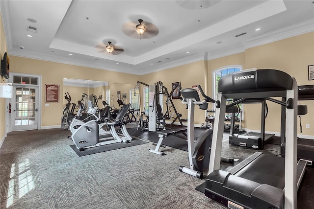 exercise room featuring a healthy amount of sunlight, a ceiling fan, a tray ceiling, and visible vents