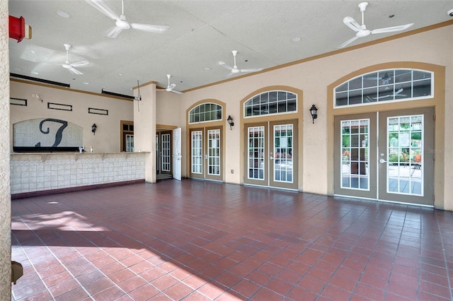 unfurnished living room with ornamental molding, a ceiling fan, and french doors