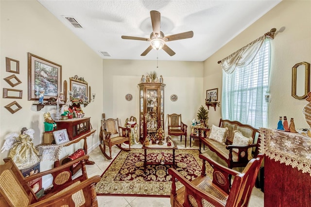 living area with tile patterned flooring, ceiling fan, and visible vents