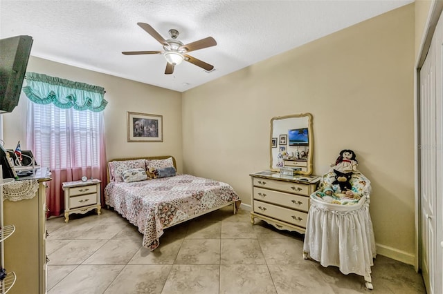 bedroom with baseboards, a textured ceiling, ceiling fan, and light tile patterned flooring